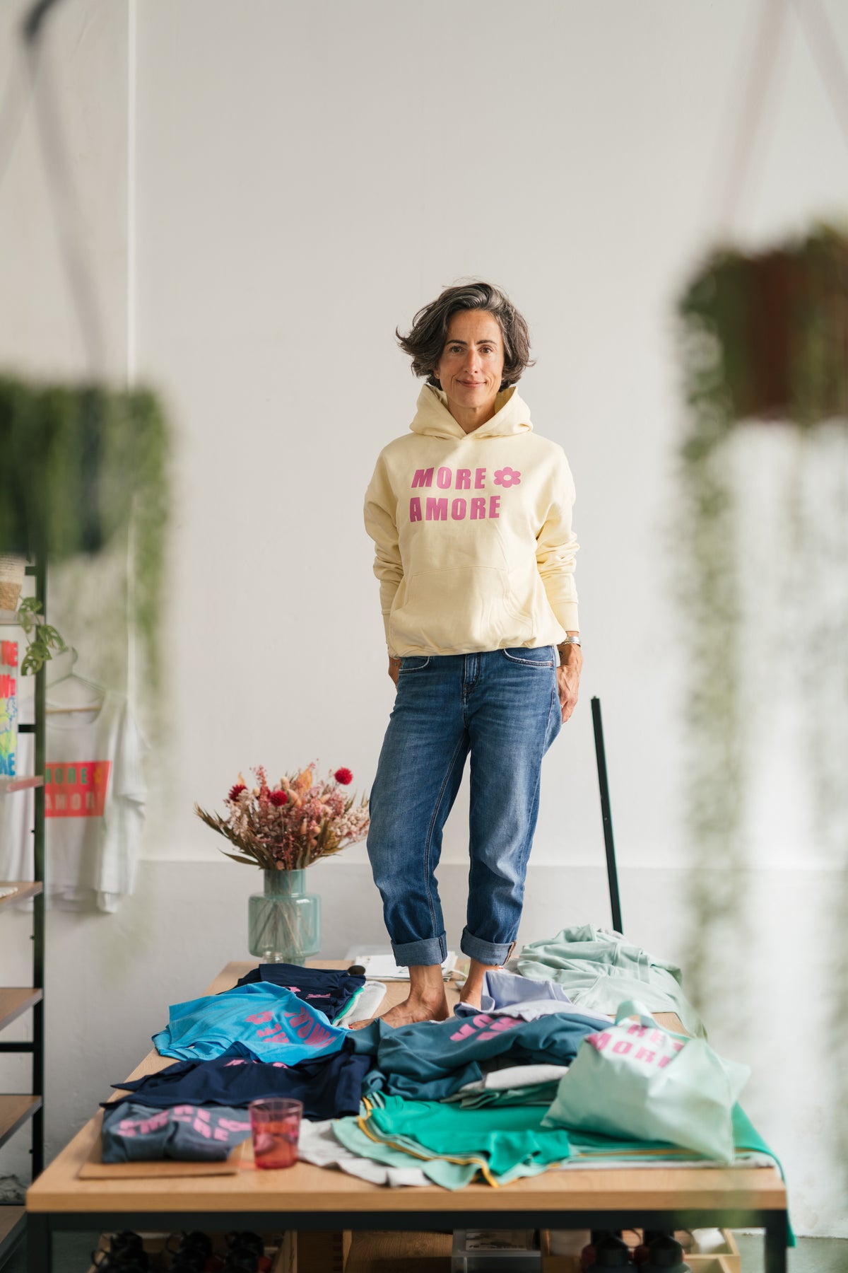 MORE AMORE Boxy Unisex-Hoodie in Soft Yellow mit pinkem Frontprint – getragen im Atelier