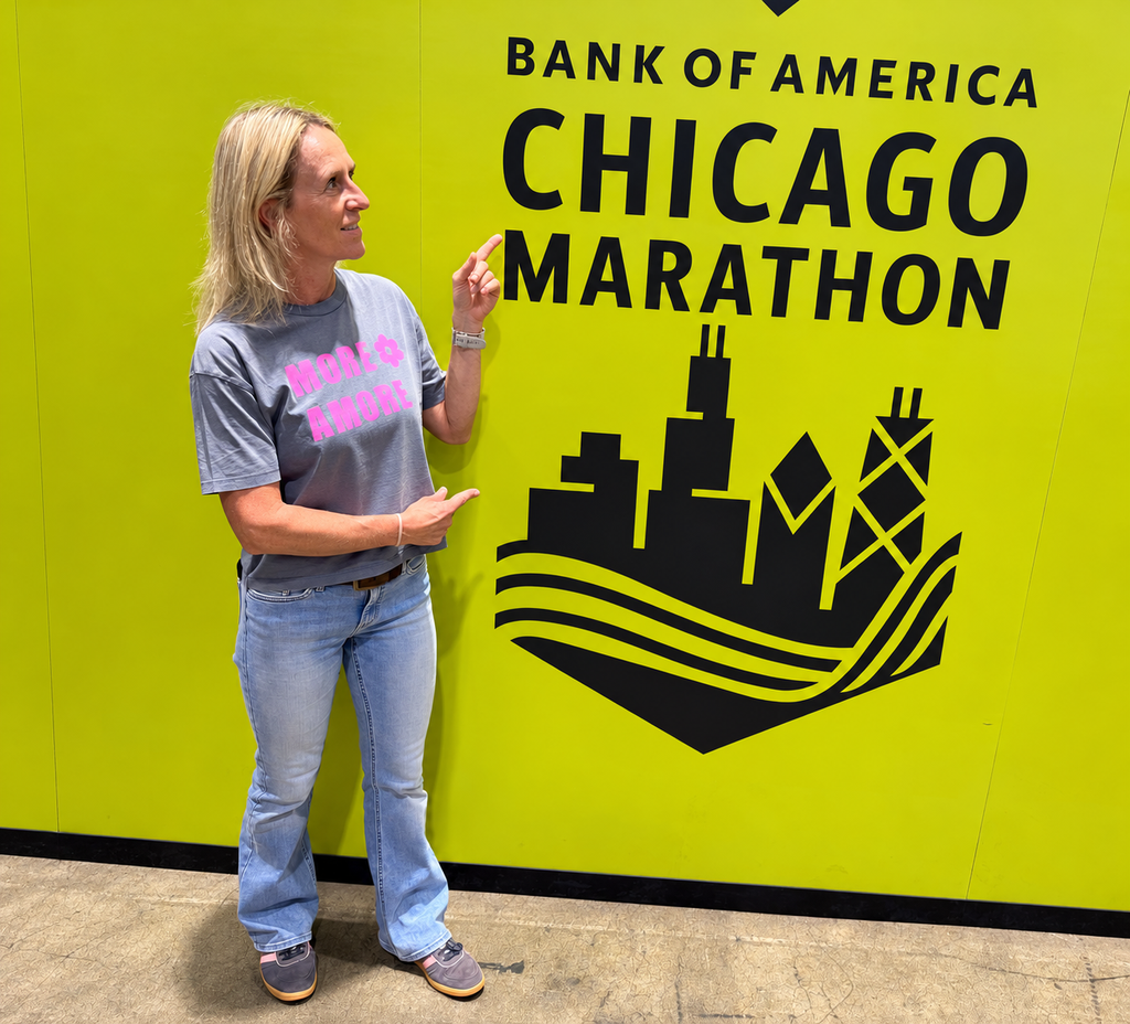 Karin im MORE AMORE Vintage Blue Cropped T-Shirt mit pinkem Frontprint vor der gelben Chicago-Marathon-Wand.