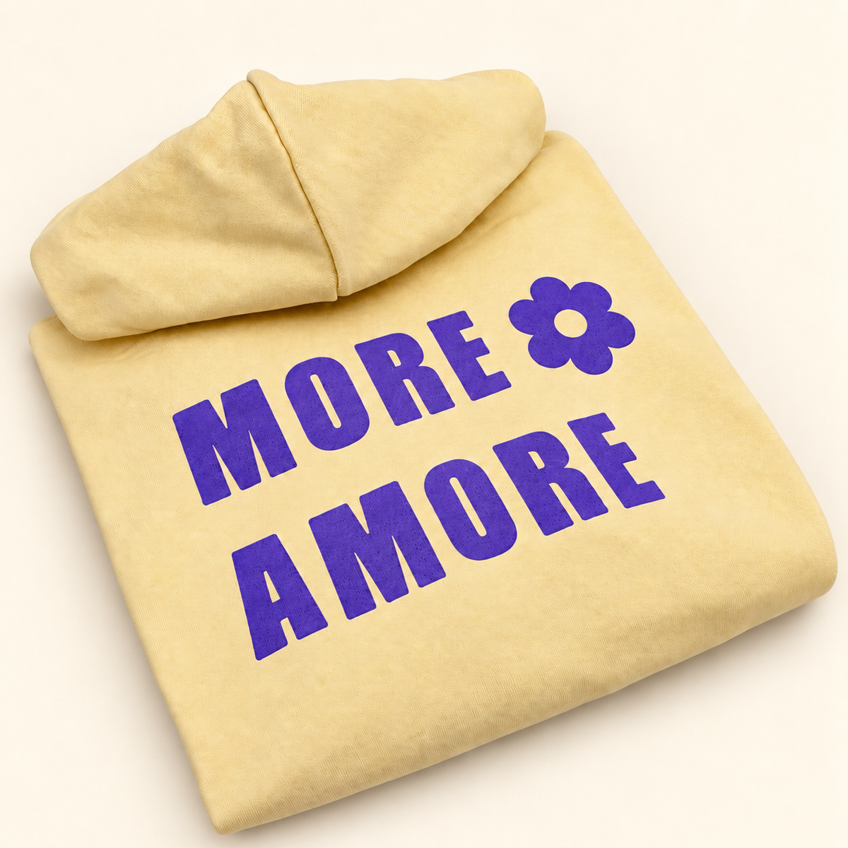 MORE AMORE Boxy Unisex-Hoodie in Soft Yellow mit Purple-Print – schräg gefaltete Ansicht