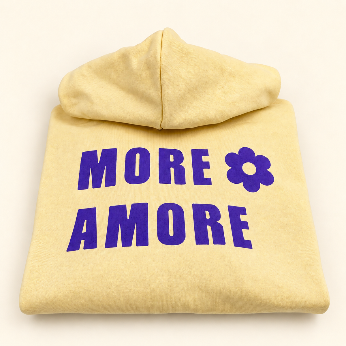 MORE AMORE Boxy Unisex-Hoodie in Soft Yellow mit Purple-Print – gerade gefaltete Vorderansicht