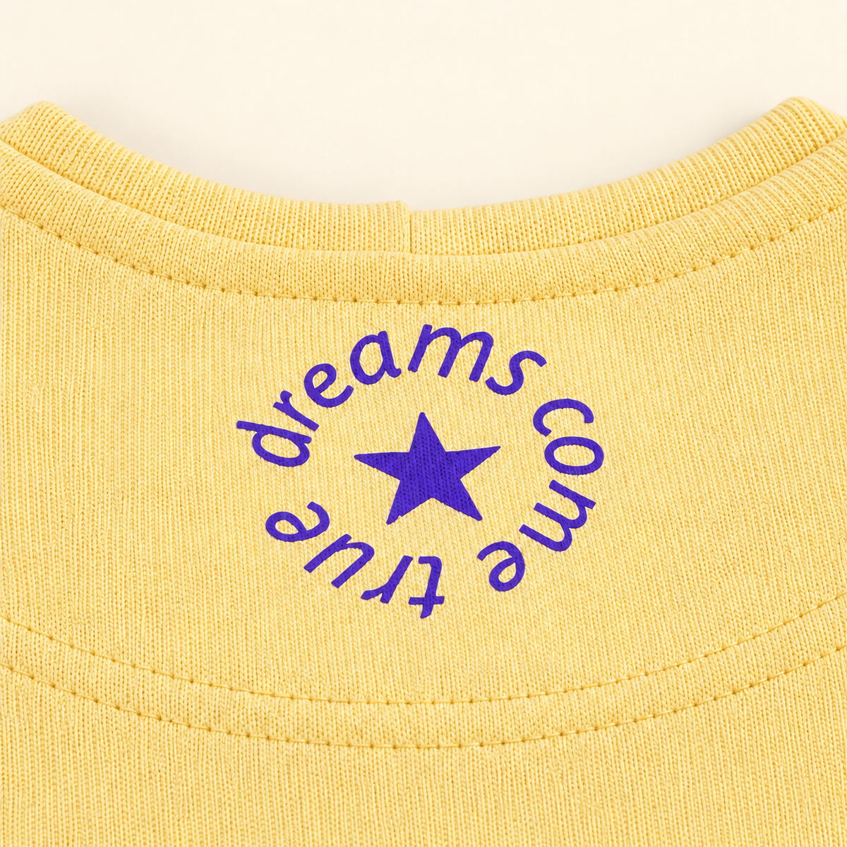 MORE AMORE Boxy Unisex-Hoodie in Soft Yellow – Detail des violetten Nackenprints mit Stern