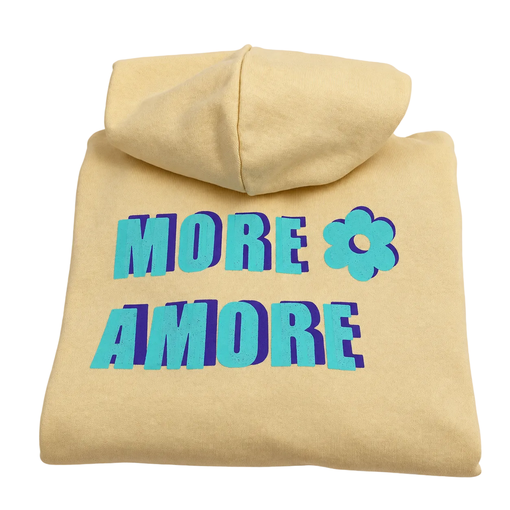 MORE AMORE Boxy Unisex-Hoodie in Soft Yellow mit türkisem Print und violettem Schatten – gefaltete Vorderansicht