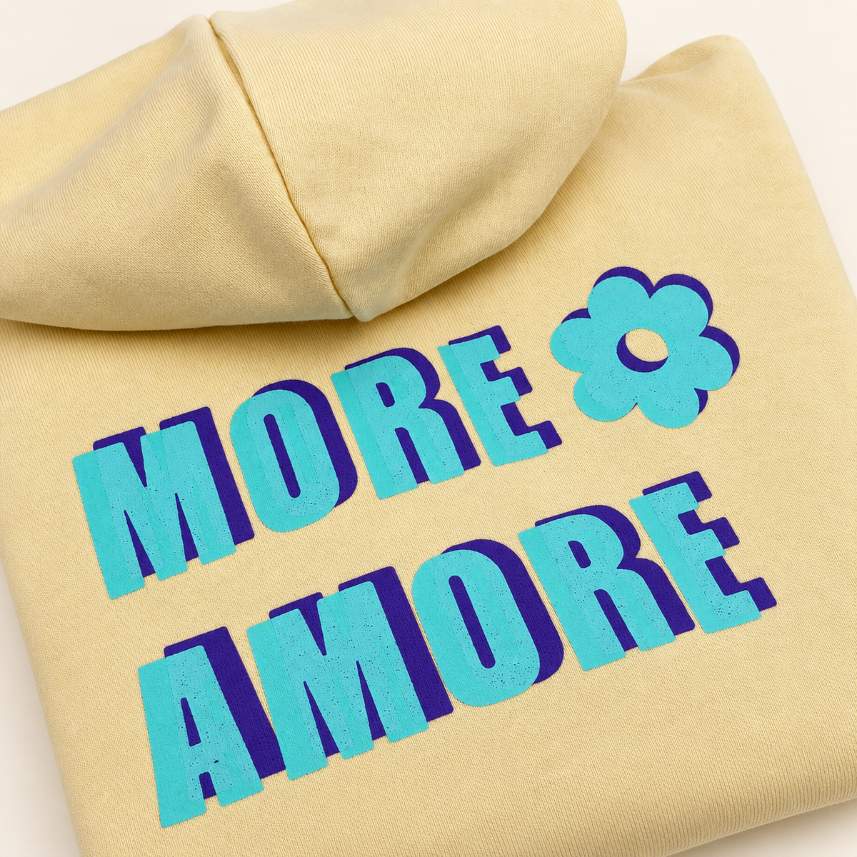 MORE AMORE Boxy Unisex-Hoodie in Soft Yellow – Detail des türkisen Handprints mit violettem Schatten