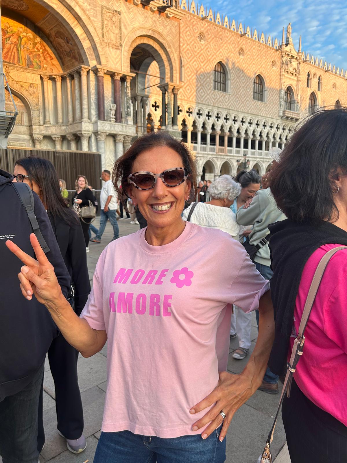 Rosi lächelt mit Sonnenbrille und Peace-Zeichen im MORE AMORE Vintage Blush Cropped T-Shirt mit pinkem Frontprint.