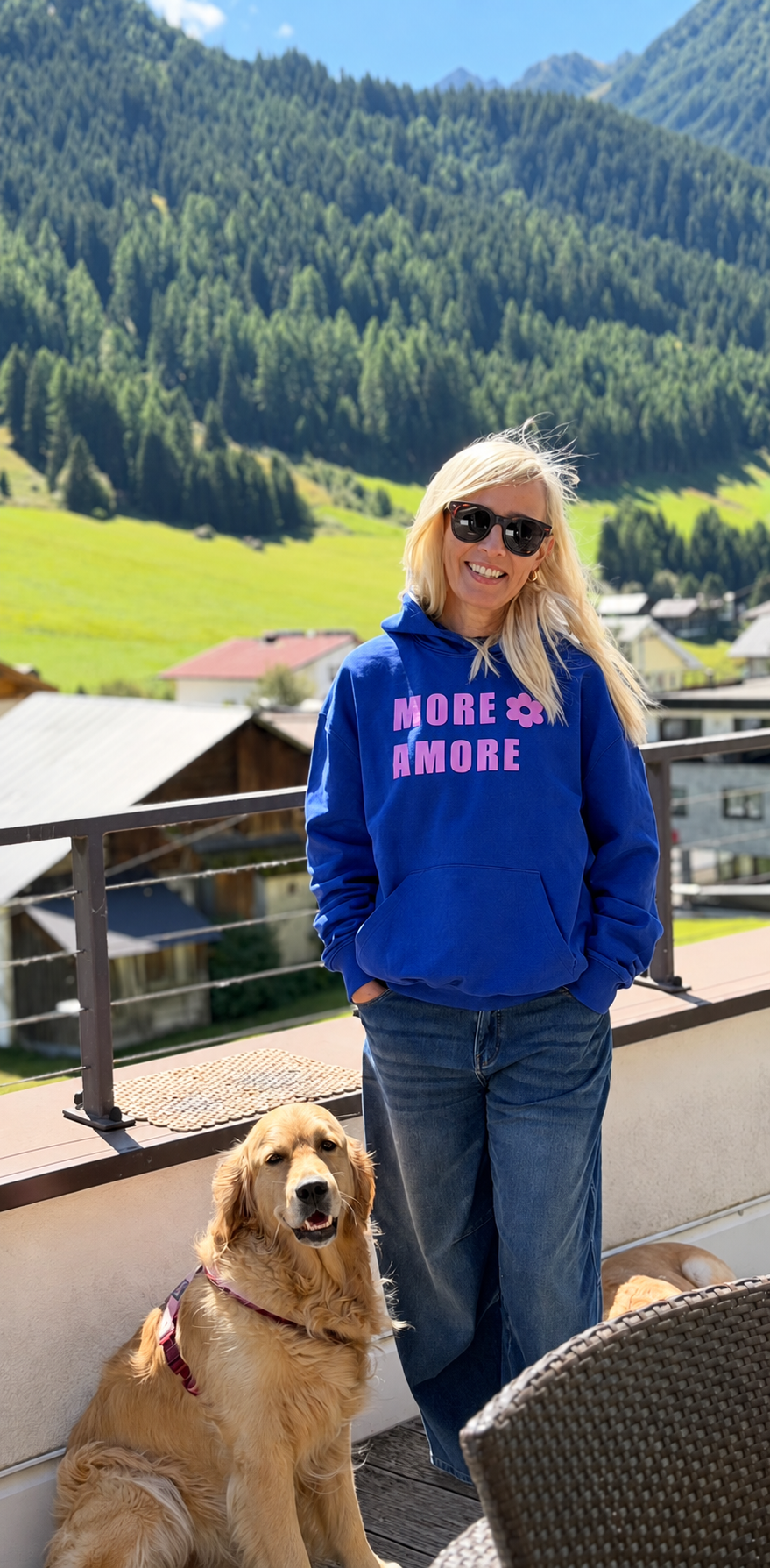 SARAH – MORE AMORE Boxy Unisex-Hoodie in Royal Blue mit pinkem Handdruck, getragen in den Tiroler Bergen